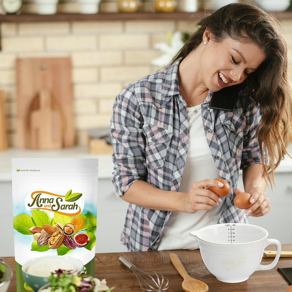 A woman holding two eggs to prepare something in the kitchen with Organic Walnuts resealable pack on the kitchen table by Anna and Sarah