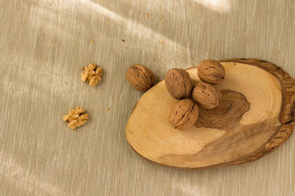 Walnuts in Shell on the wooden piece on beige ground  by Anna and Sarah